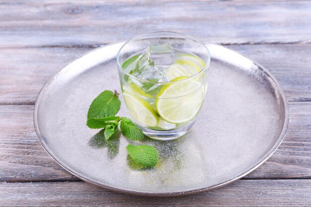 Lemonade in glass on tray on wooden background