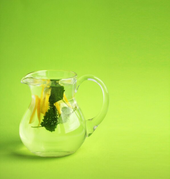 Photo lemonade in a jug on a green background cold water for detoxification with lemon and mint