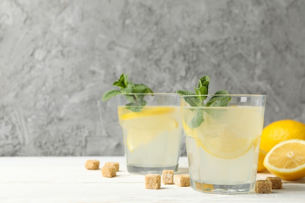 Lemonade, lemons and sugar cubes on wooden surface