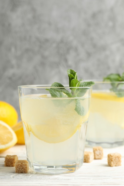 Lemonade, lemons and sugar cubes on wooden surface