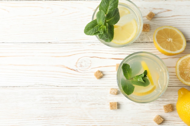 Lemonade, lemons and sugar cubes on wooden surface