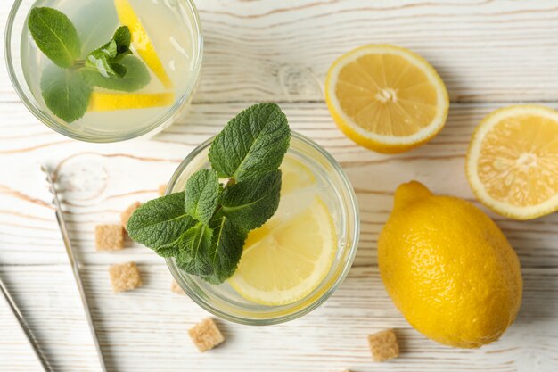 Lemonade, lemons and sugar cubes on wooden surface