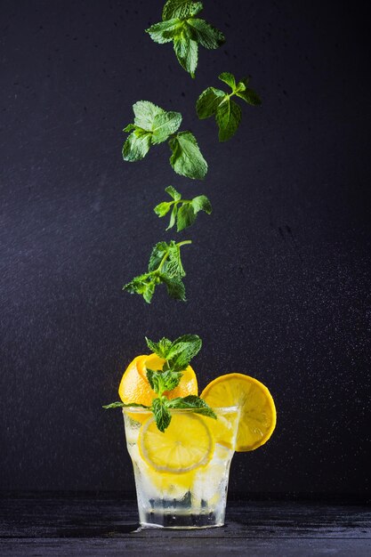 Lemonade met vliegende munt en citroen Zomer verfrissend drankje met citroen op donkere achtergrond
