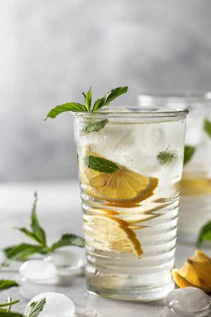 Лимонад или коктейль мохито с лимоном и мятным летним освежающим напитком со льдом на сером фоне