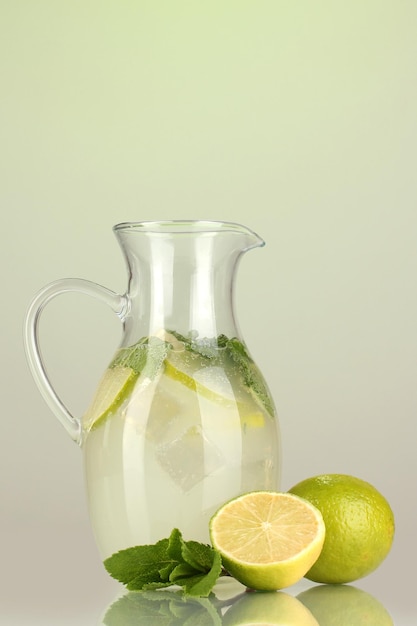 Lemonade in pitcher on green background