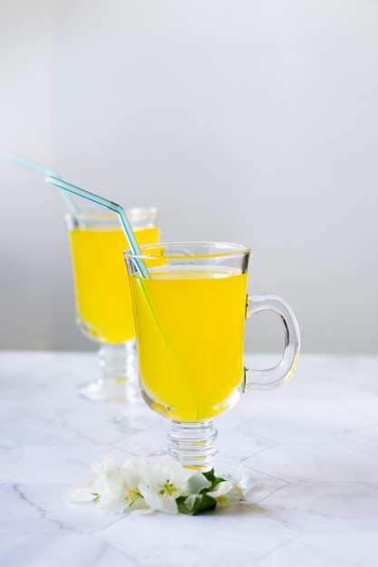 Lemonade refreshing drink in a glass beaker on a light background