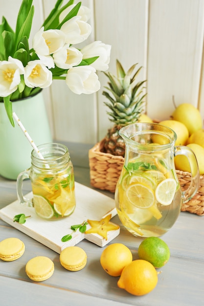 Lemonade, sweet macarons, fruits and tulip flowers