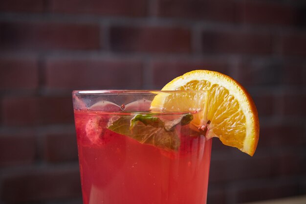 Lemonade on table mint and lemon wedge glass with straw brick wall on background closeup macro