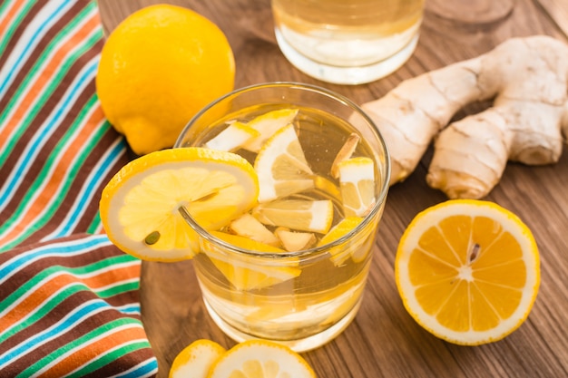 Lemonade with lemon and ginger in a transparent glass on a wooden table