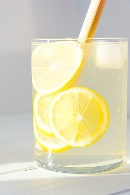 Photo lemonade with lemon and ice in a glass.