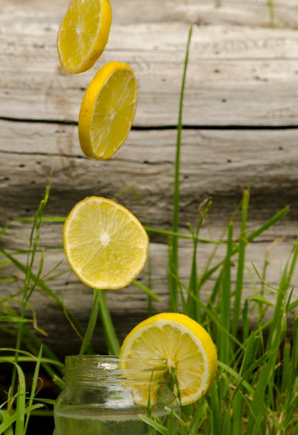 lemonade with lemons falling on natural background