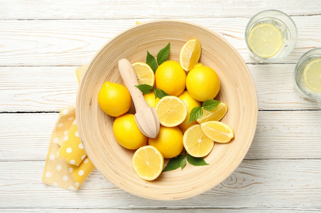 Lemonades and bowl with lemons on wooden surface