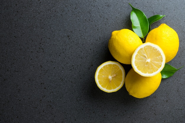 The lemons are on top of black stone kitchen table. 