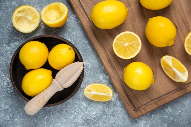 Lemons on cutting board in bowl sliced and full mixed grey backround