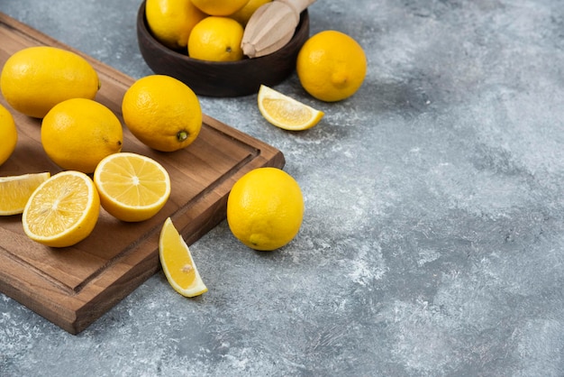 Lemons on cutting board in bowl sliced and full mixed grey backround