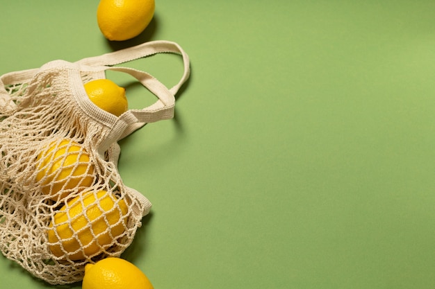 Lemons in an eco-friendly bag on a green surface