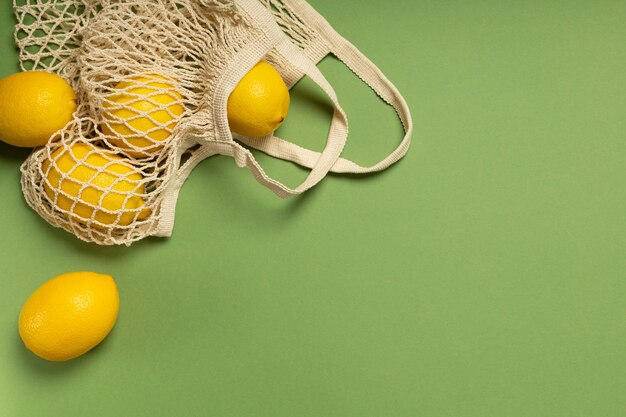 Lemons in an eco-friendly bag on a green surface