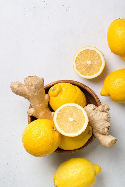 Lemons and ginger in bowl on a white. vertical top view