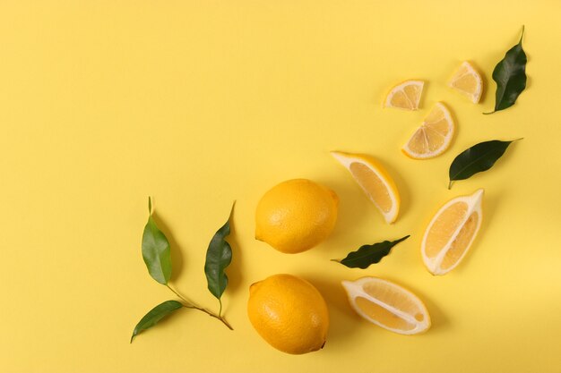 Lemons and green leaves on a colored background