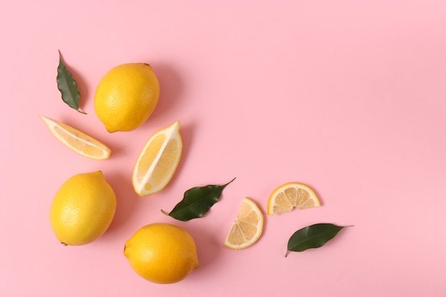 Lemons and green leaves on a colored background