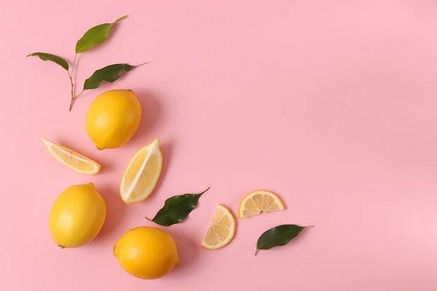 Lemons and green leaves on a colored background