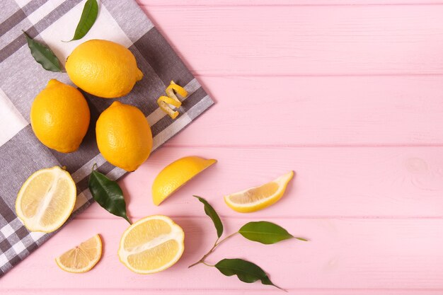 Lemons and green leaves on a colored background