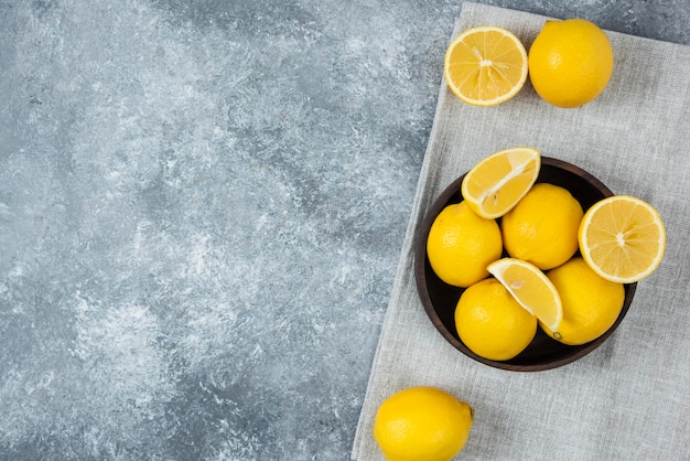 Lemons on grey backround wooden bowl