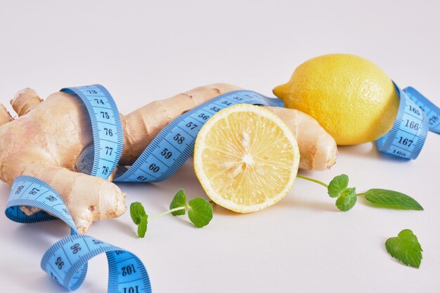 Lemons, mint leaves, ginger root and blue measure tape on gray background copy space