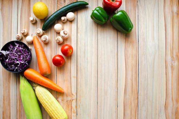 Lemons,tomatoes, cucumbers,apples, bell peppers, carrots, mushrooms, corn, put on a wooden table to make a salad.Health care concept.copy space