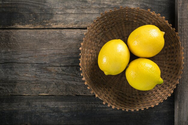 Lemons in wicker plate on wooden background