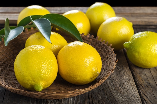 Lemons in wicker plate on wooden background