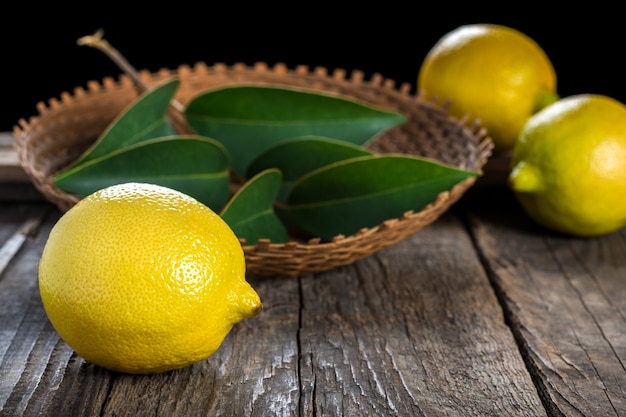 Limoni in piatto di vimini su fondo di legno