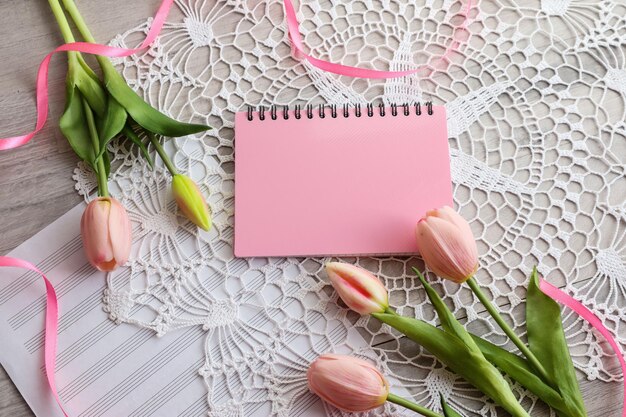 Foto lente achtergrond tulpen en een notitieboekje op een open werk servet top view