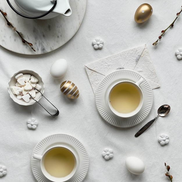 Lente afternoon tea lente poesje wilgen bloemen witte theepot en thee kopjes op tafel plat leggen van wit textiel tafelkleed paaseieren witte keramische kopjes en suiker