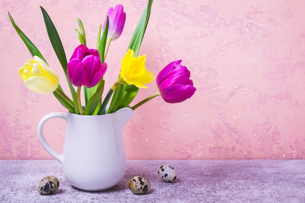 Lente boeket van tulpen en narcissen in een witte vaas. Pasen-groetkaart