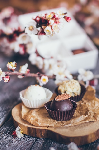 Lente collectie handgemaakte chocolade bonbons snoepjes en kersen bloemen decoratie op rustieke houten achtergrond.