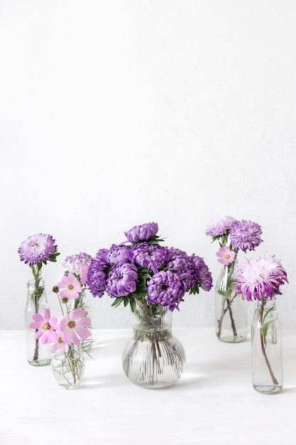 Lente compositie met chrysant bloemen in glazen vazen op een wazig witte achtergrond, kopieer ruimte.