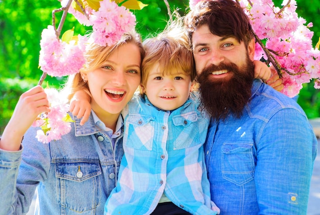 Lente gelukkige familie in sakura tuin moeder vader en zoontje samen in bloeiend park