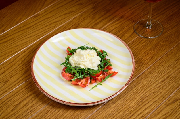 Lente groentesalade met tomaten op witte plaat op houten achtergrond