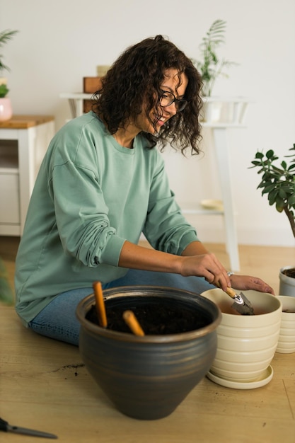 Lente hobby gelukkige jonge vrouw verplanten in bloempot kamerplant met vuil of grond thuis Tuinplant en groen tropisch concept