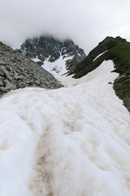 Lente in de bergen. Sneeuw en morene op de bergkam. Bewolkt weer. Landschap onder de piek Ushba. Zemo Svaneti, Georgië, Kaukasus