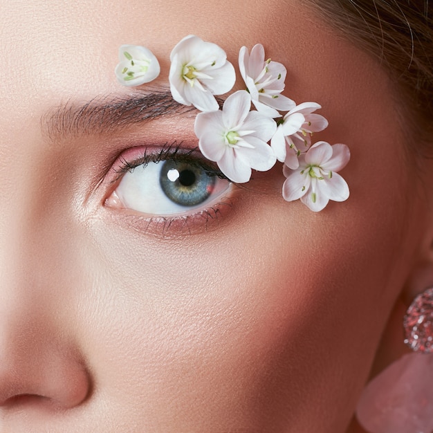 Lente make-up oog vrouw met witte bloemen.