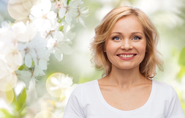 Foto lente, natuur en mensen concept - lachende vrouw in blanco wit t-shirt over kersenbloesem achtergrond