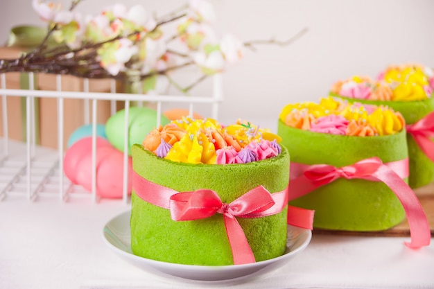 Lente Pasen feestelijke tafel. Kleine groene taarten met boter crème bloemen en kleurrijke eieren.