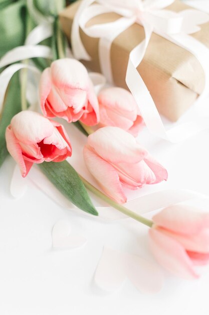 Lente roze tulpen met lint en geschenkdoos op witte achtergrond Stijlvolle zachte verticale afbeelding van lentebloemen Happy Womens Day Wenskaart mockup Happy Mothers Day