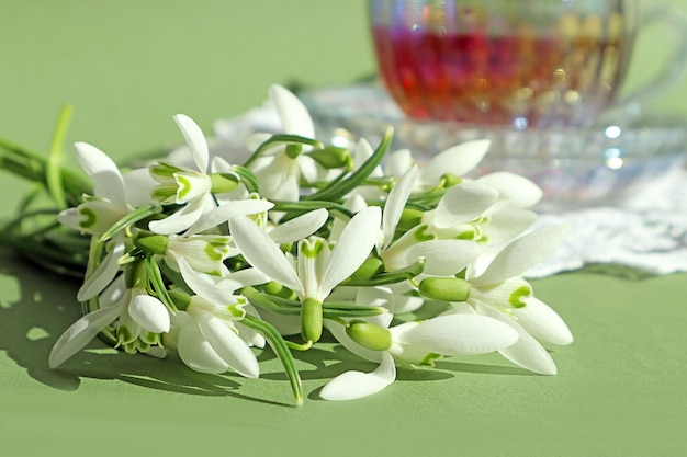 Lente stemming een boeket sneeuwklokjes tegen de achtergrond van een kopje thee op een pastel achtergrond close-up