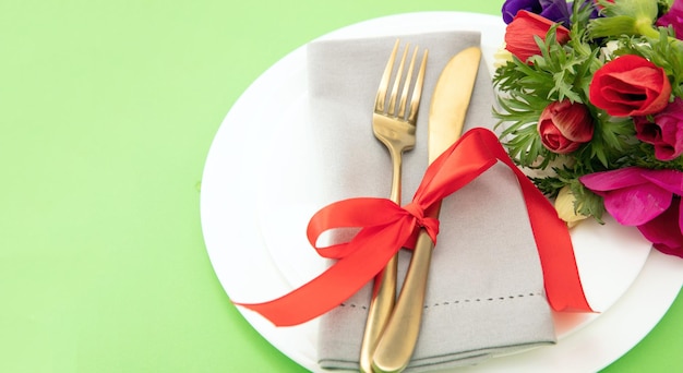 Lente tafelschikking Wilde bloemen decoratie servet en bestek op borden pastel groene achtergrond