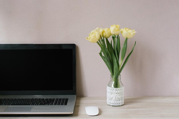 Lente thuiskantoor stilleven compositie leeg laptopscherm gele tulpen in een vaas