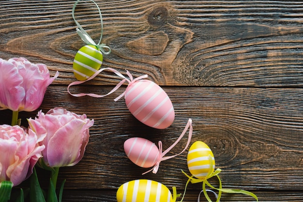 Lente tulpen en veelkleurige paaseieren op een houten achtergrond