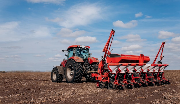 Lente zaaiseizoen boer met een tractor zaait maïszaden op zijn veld maïs planten met getrokken planter landbouw zaaien het concept van landbouw en landbouwmachines